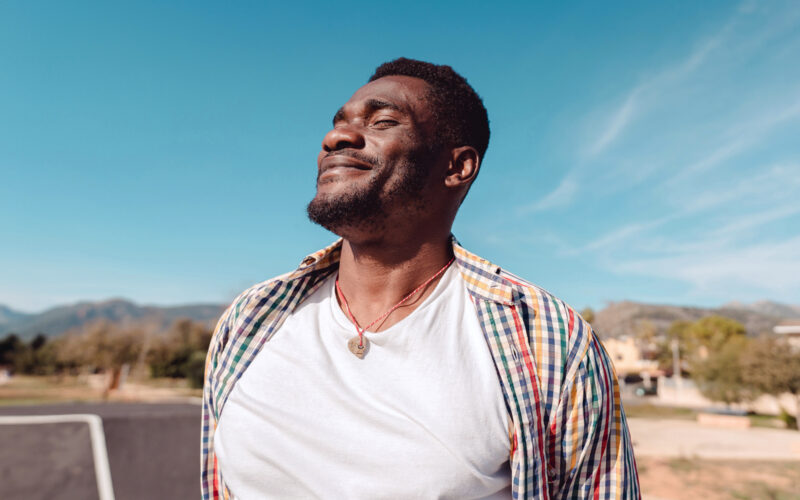 man facing the sun with a smile