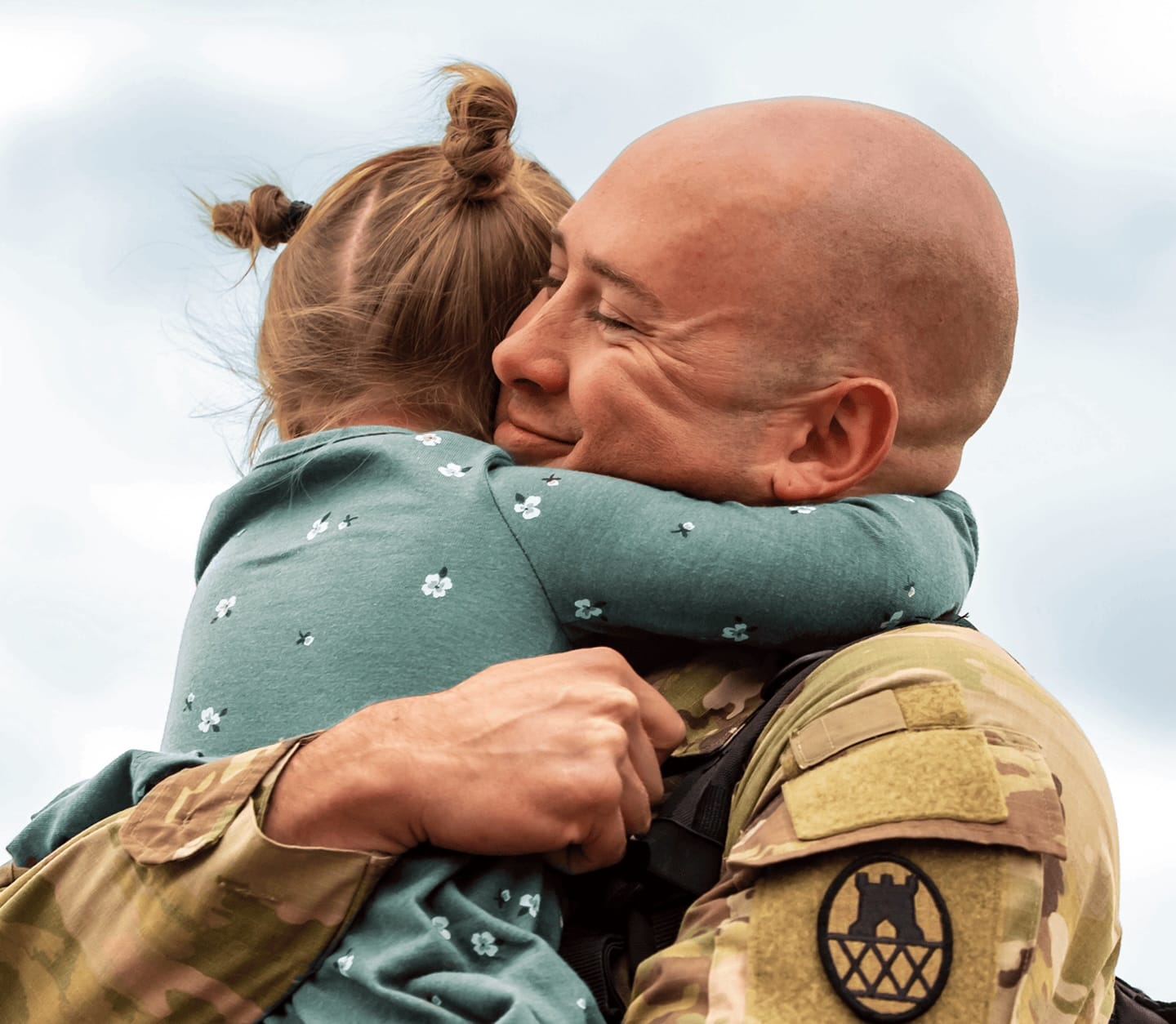 man in military uniform hugging daughter