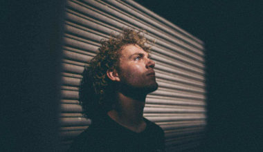 guy in darkness leaning on metal wall