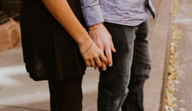 couple standing front to back loosely holding hands