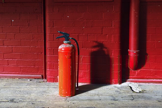 A red fire extinguisher on a red wall