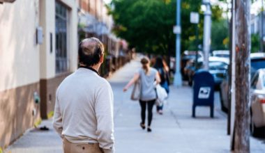 man looking down the sidewalk of a woman walking down the street