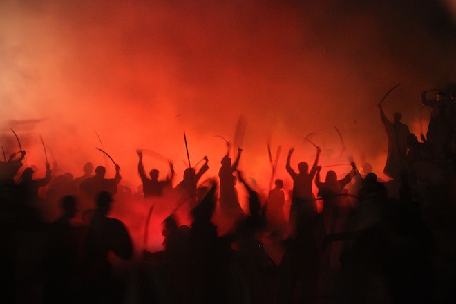 a mob of people surrounded by smoke and red light