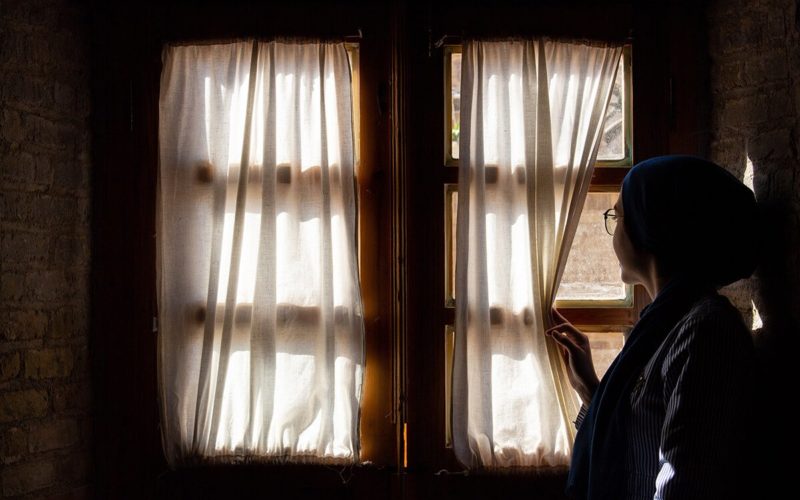 woman staring out of closed window