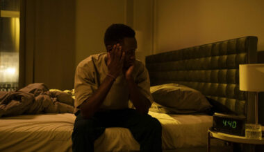 man sitting on bed with face in his hands