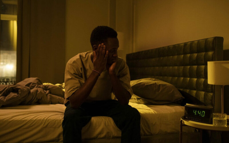 man sitting on bed with face in his hands