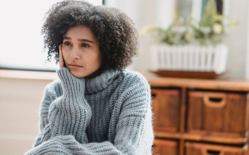 woman in grey sweater sitting looking sad