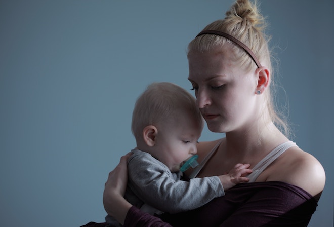 A mother holds her baby in a low lit room