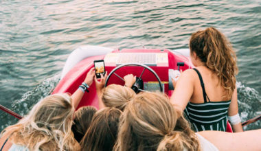 group of girls on a boat staring at a phone