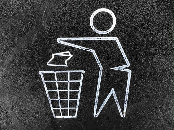An illustration of a person throwing something into the trash bin