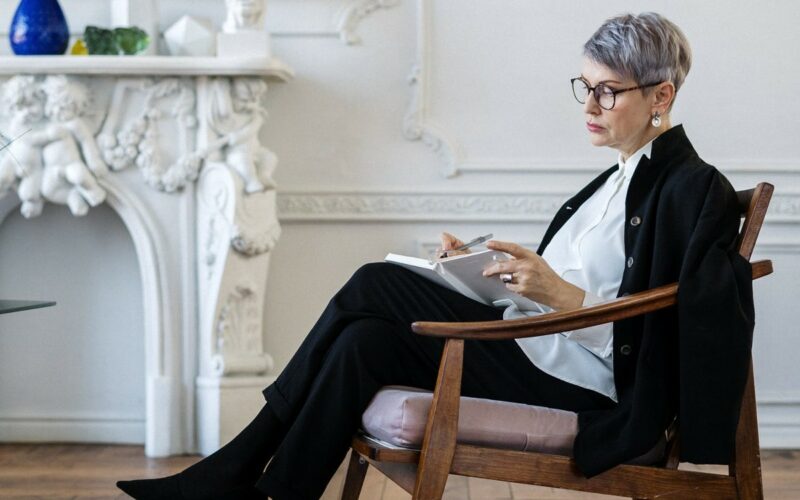 woman sitting on chair taking notes