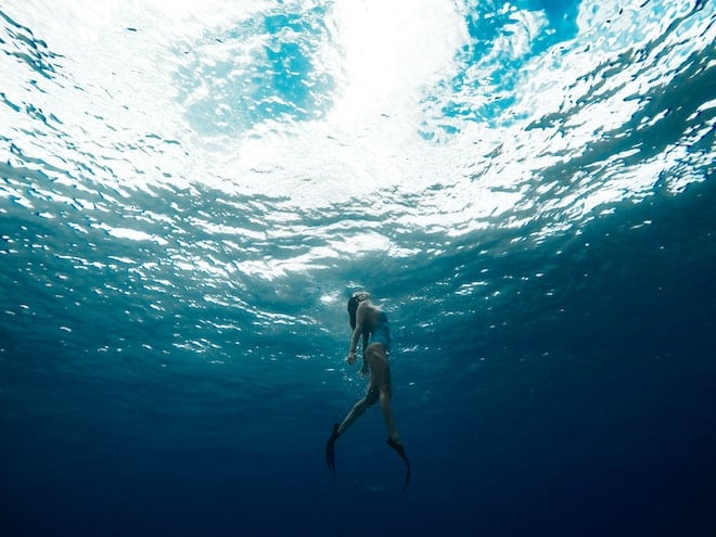 A woman swims toward the surface of the ocean