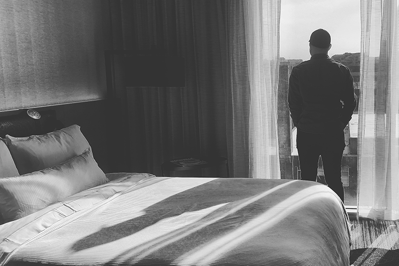 Man silhouetted looking out bedroom window